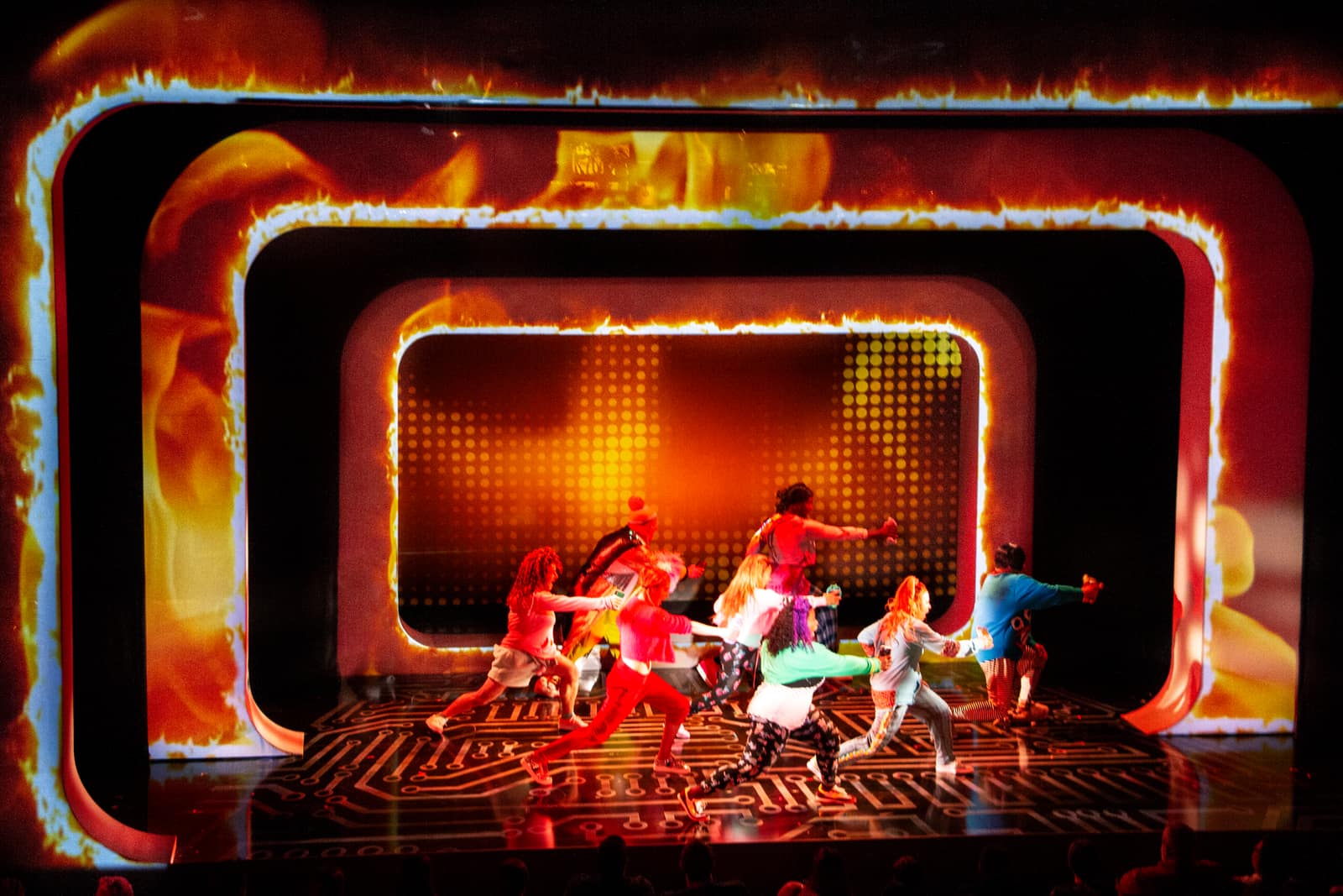 The portal frames washed in fiery orange as the Be More Chill company dances centre stage.
