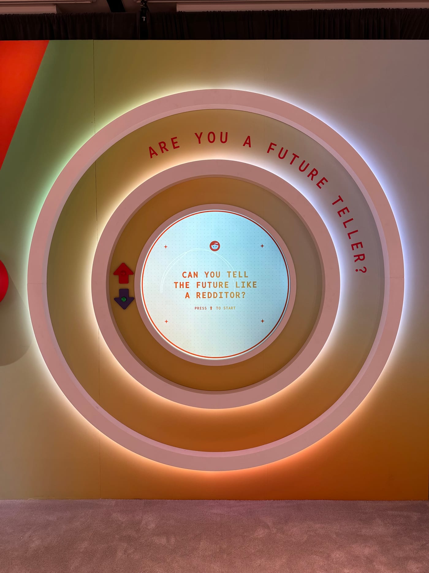 The Reddit Prediction Analyzer — a backlit concentric-ring installation reading ’Are you a future teller?’, a circular game screen and arrow buttons at its center.