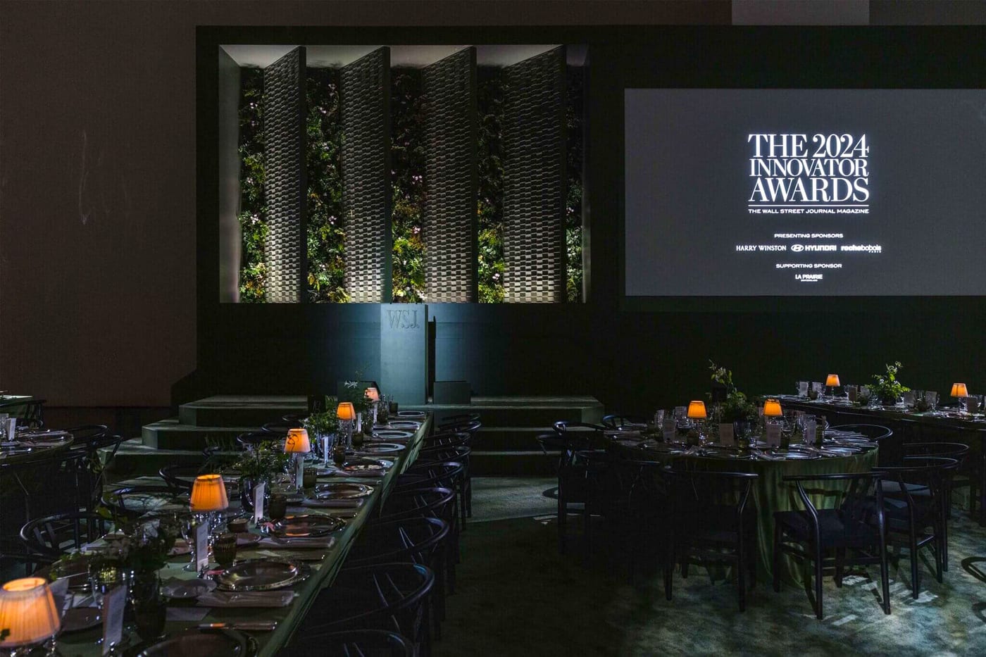 A dinner hall with ’The 2024 Innovator Awards’ projected across the wall.
