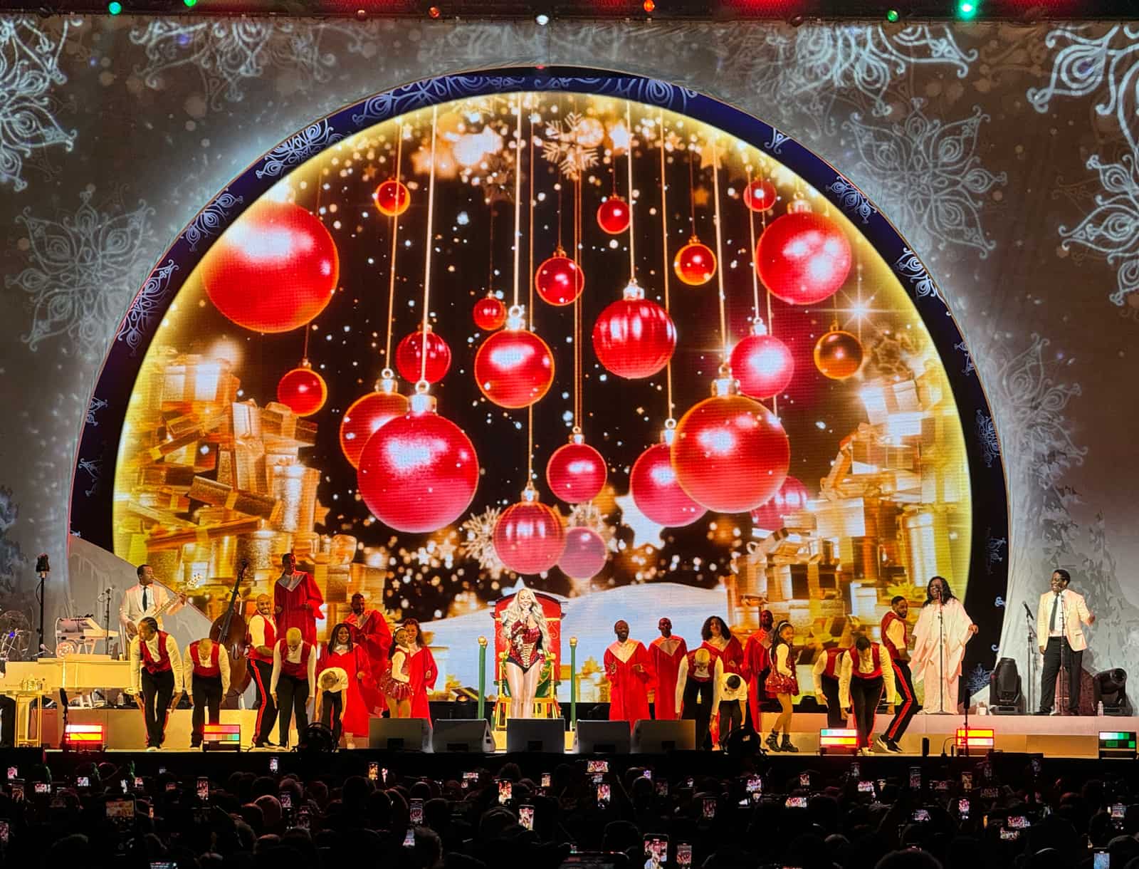 Giant red ornaments suspended across the golden domed LED as a choir in red and white performs below.