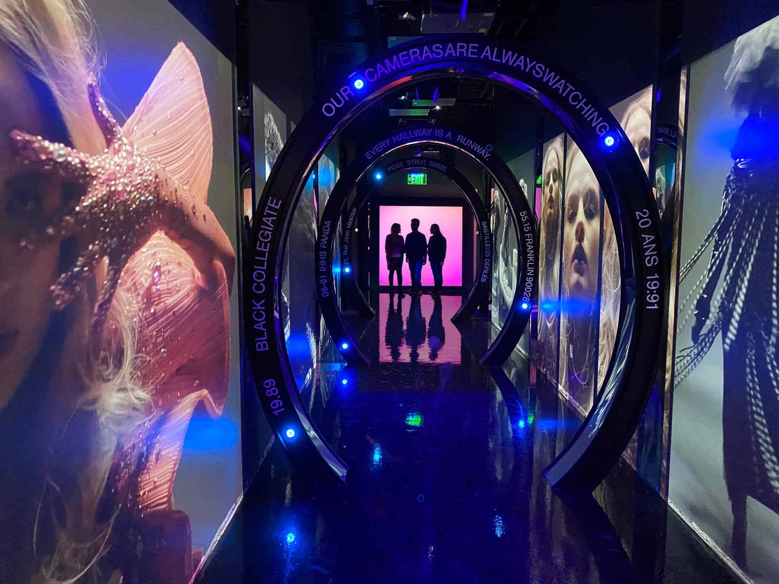 The mirrored video corridor at the entrance to Modelland — a reflective passage with figures silhouetted against the lit far end.