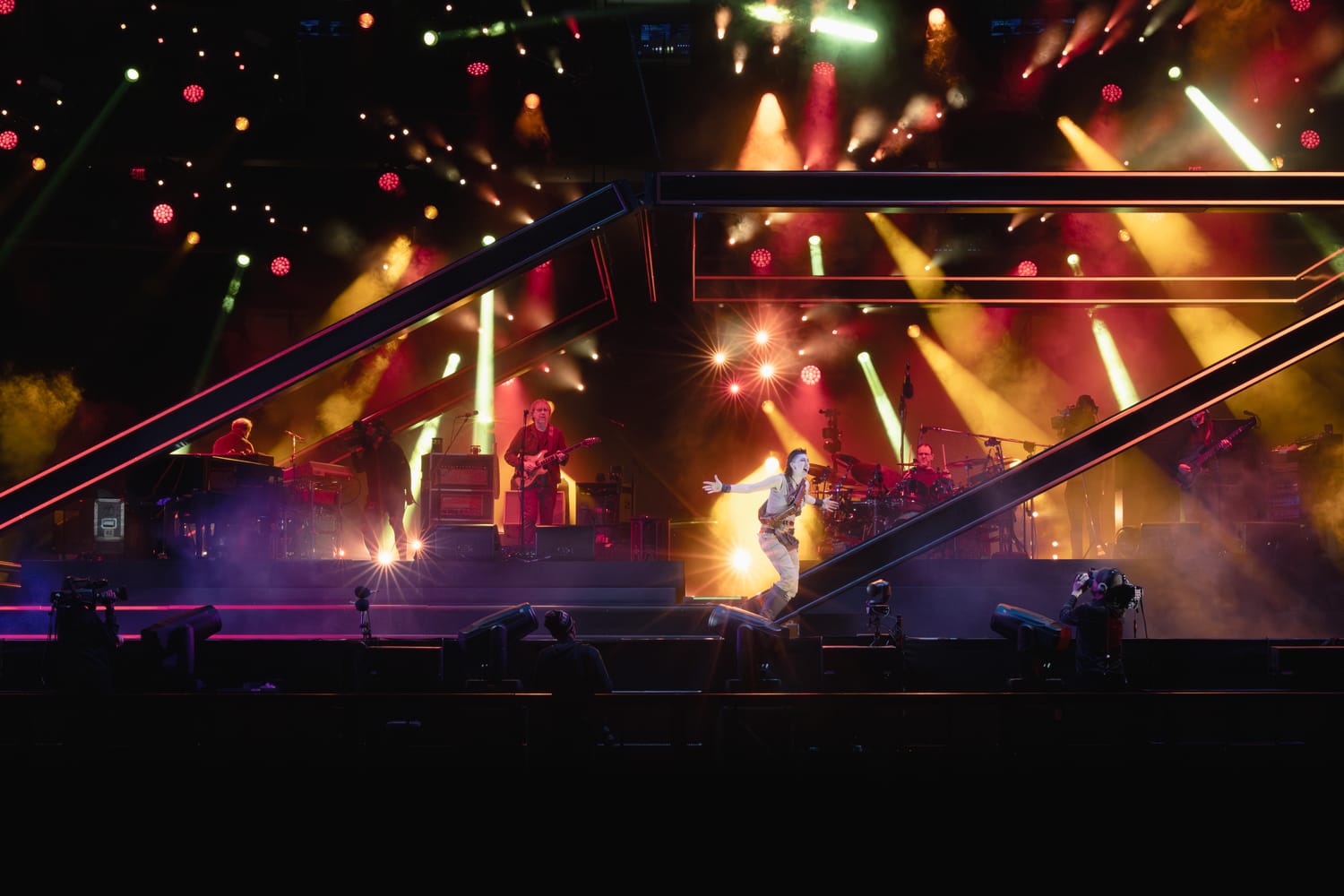 Phish on the Madison Square Garden stage inside the angular LED frame, washed in warm gold and red light with pyro during Gamehendge.